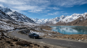 Telugu films exotic locations: a lone car on an empty Ladakh mountain road under snow peaks
