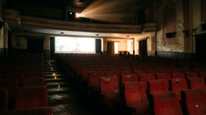 Raja Saab review — near-empty cinema auditorium with projector beam and scattered empty seats